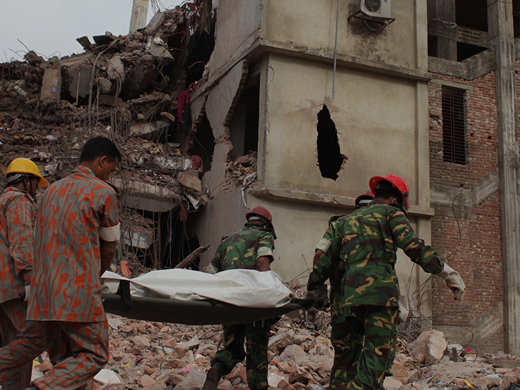 Building in ruble while emergency workers recover a body