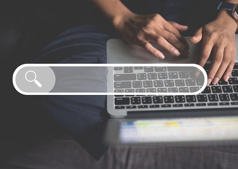 Hands of businesswoman on computer laptop on sofa in home. with a search bar overlaid on the image.